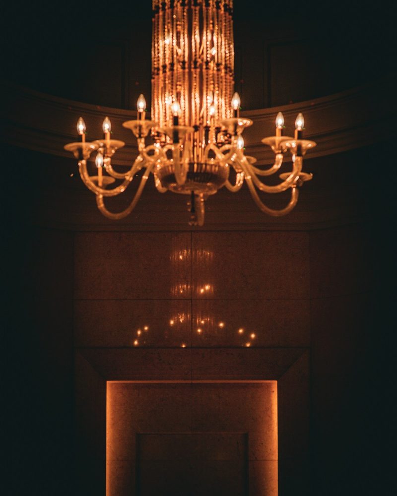 Cascading crystal chandelier with a warm amber glow set against a limestone-clad interior