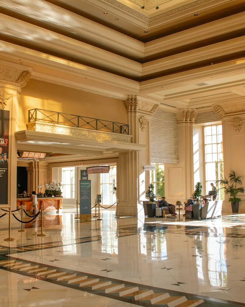 Grand hotel lobby with ornate columns, marble floor, and sunlight