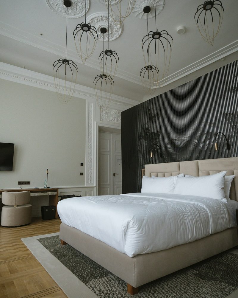 Grand hotel suite with ornate ceiling molding, decorative pendants, and herringbone wood floor