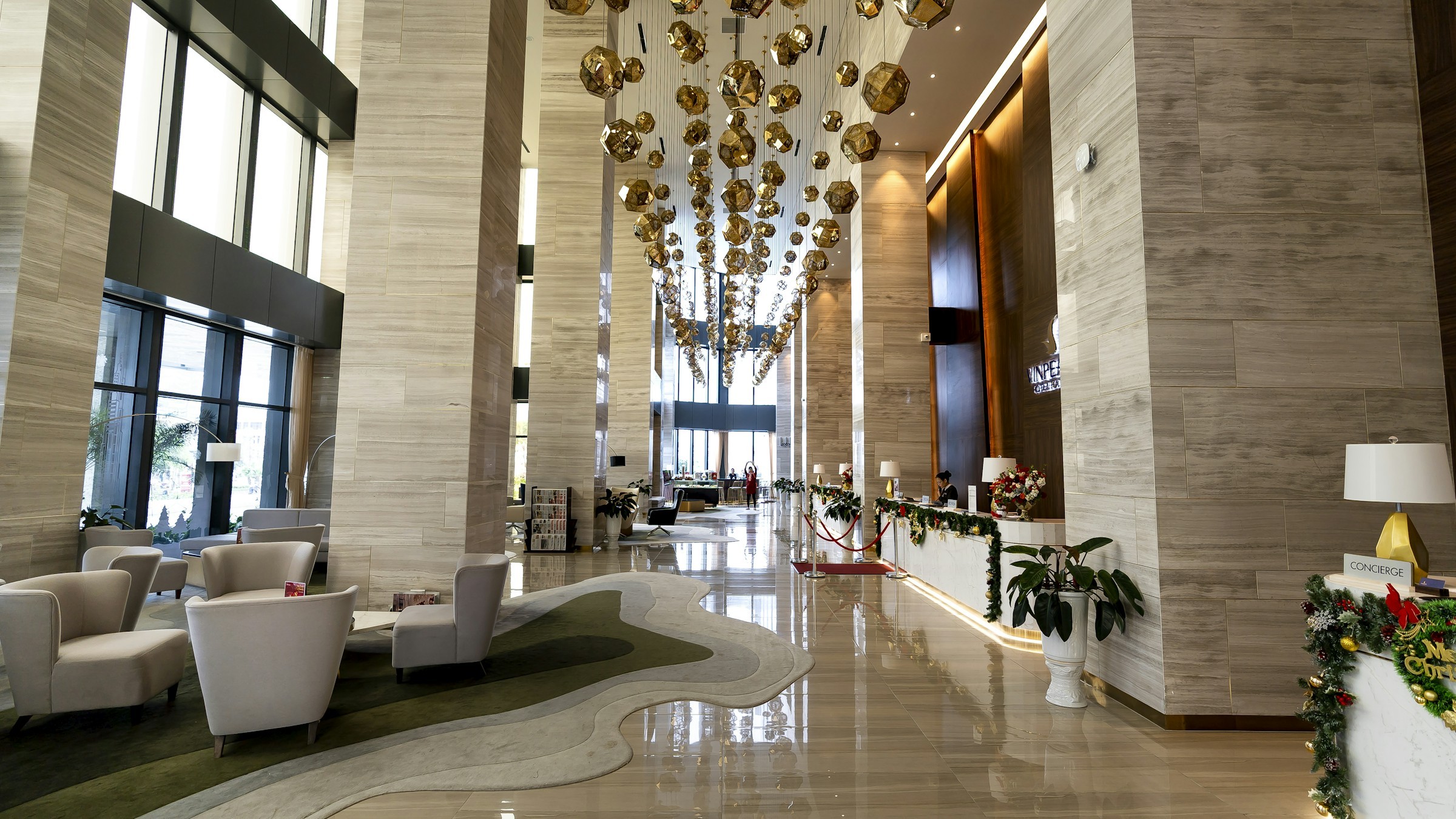 Elegant hotel lobby with cascading gold chandeliers, marble floors, and lounge seating